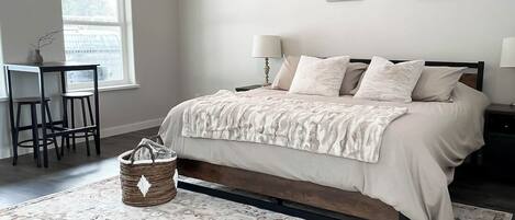 A bedroom with a bed, bedside tables, a ceiling fan, a window, and artwork on the wall.