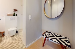 Ein modernes Badezimmer mit Toilette, Sitzbank, Spiegel und einem gemusterten Teppich.