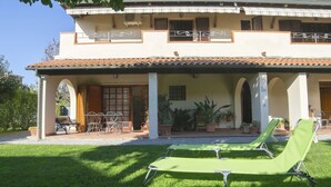 A two-story building with a covered patio area, outdoor seating, and potted plants. - San Gaetano apartment in Follonica (Follonica)