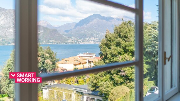 Vista desde una ventana sobre un lago, montañas y edificios residenciales.