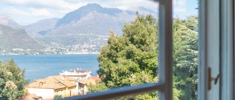A view from a window overlooking a lake, mountains, and residential buildings.