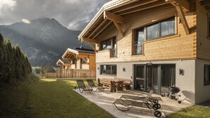 A wooden chalet with a patio, outdoor seating, and a view of mountains. - Wilderer Chalets (Leutasch)