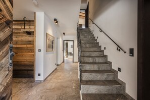 Un escalier moderne avec des marches en pierre et une rampe en métal, menant à un deuxième étage.