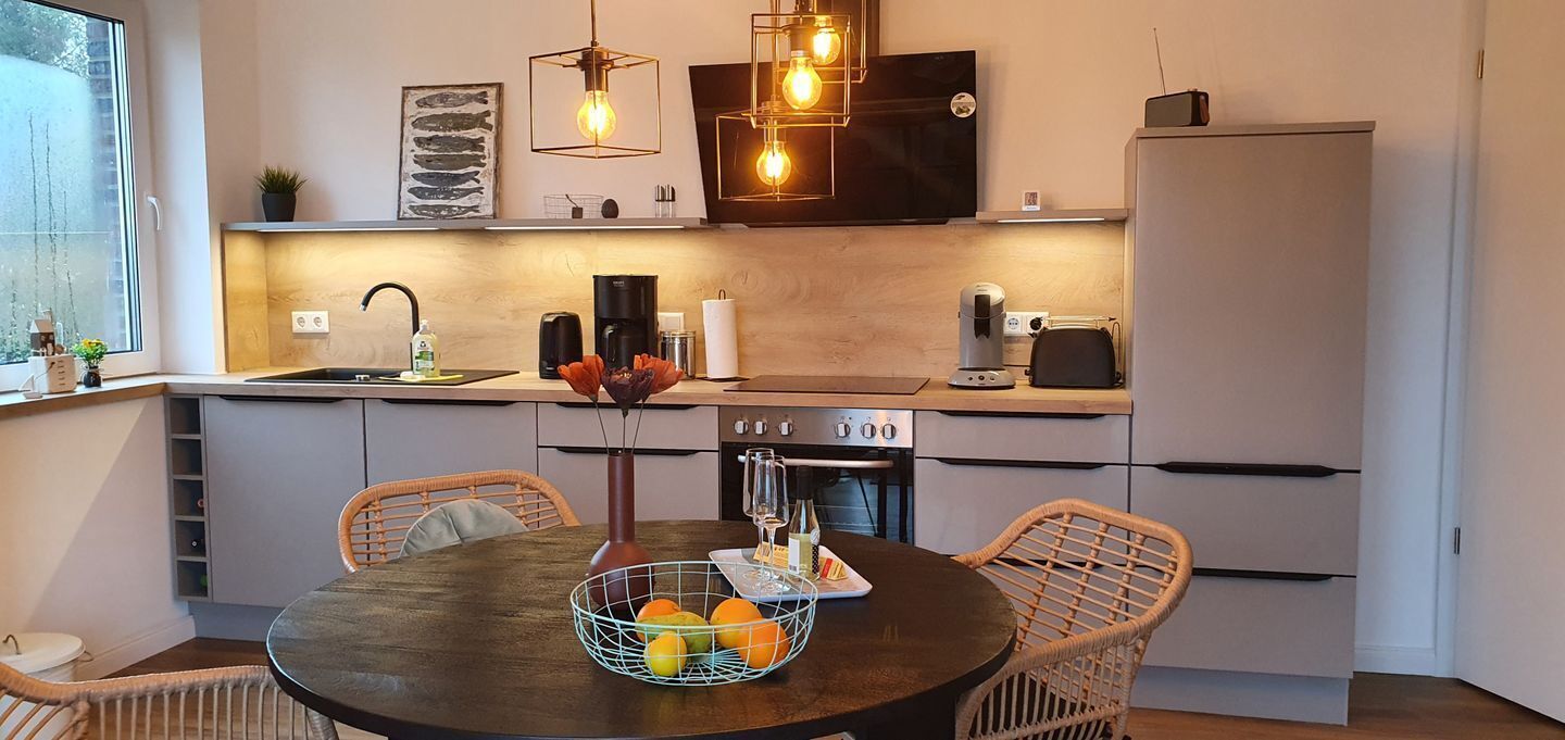 Una cucina moderna con un tavolo da pranzo, sedie e una cesta di frutta.