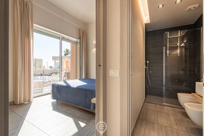 Een moderne hotelkamer met balkon, douche en bed.
