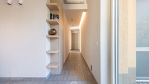 Een smalle gang met houten vloeren, inbouwkasten en een aan het plafond gemonteerde airconditioning.