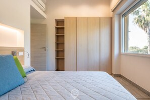 A bedroom with a bed, a wardrobe, and a window.