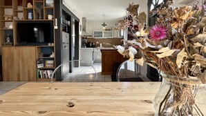 Una cocina moderna con comedor, armarios de madera y un jarrón con flores secas.