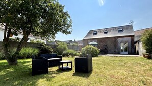 Un patio trasero con mobiliario exterior, una casa de ladrillo y un árbol grande.