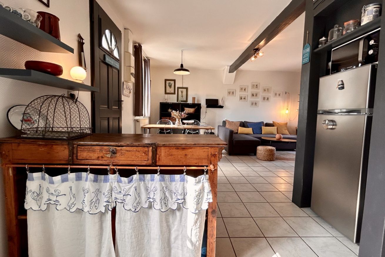 A kitchen with a wooden table, a birdcage, and a refrigerator.