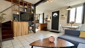 Una sala de estar con televisor, estanterías de madera, un sofá y un comedor.