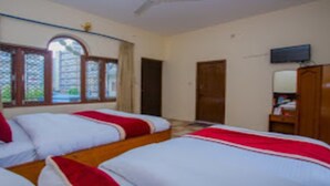 A hotel room with two beds, a television, and a window with a view of greenery. - Merostay 019 Hotel Bien Venue (Pokhara)