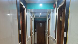 A hallway with a carpeted floor, doors on both sides, and a ceiling light. - spanish hostel (Kowloon)