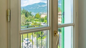 A view through a window with a metal gate, a mountain in the background, and buildings in the foreground. - Green House Regatola by Wonderful Italy (Bellagio)