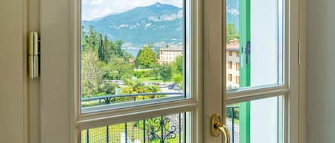 A view through a window with a metal gate, a mountain in the background, and buildings in the foreground.