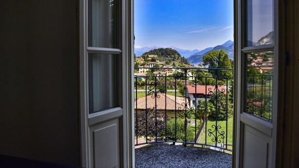 A balcony with a metal railing overlooking a mountainous landscape with houses and greenery. - Green House Regatola by Wonderful Italy (Bellagio)