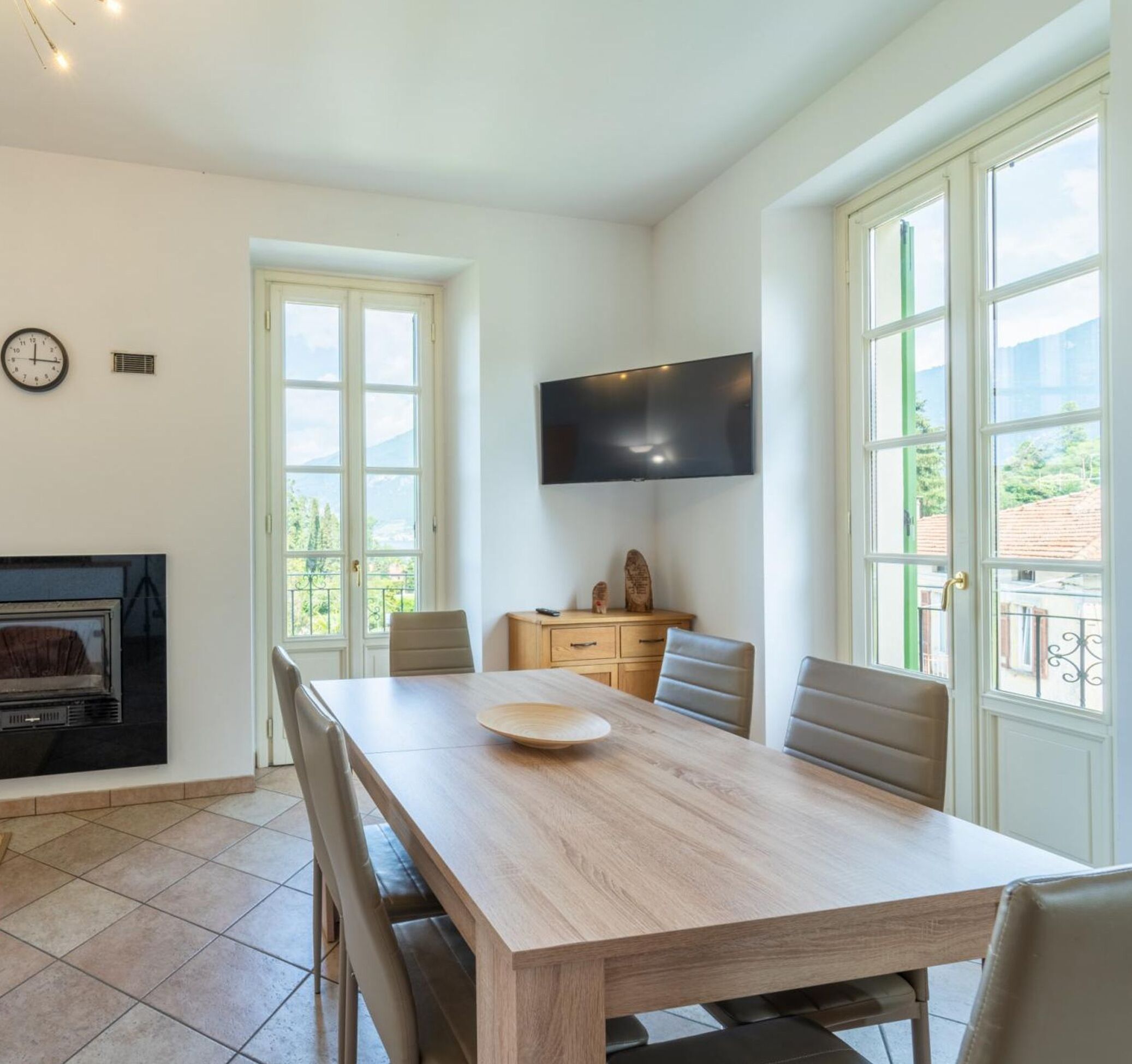 Ein Essbereich mit Holztisch, Stühlen, einem Flachbildfernseher und einem Kamin.