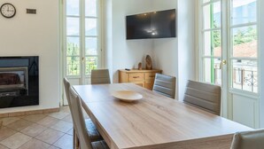 A dining area with a wooden table, chairs, a flat-screen TV, and a fireplace. - Green House Regatola by Wonderful Italy (Bellagio)