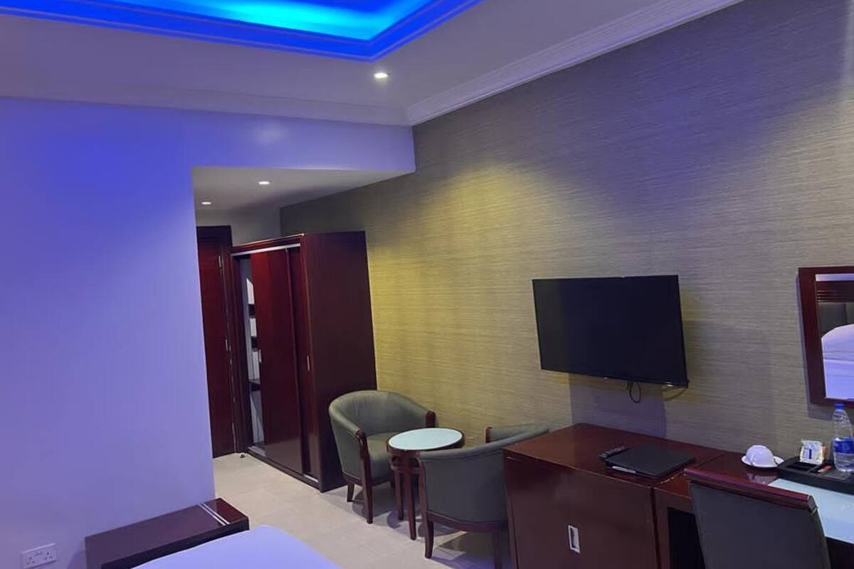 Habitación de hotel con escritorio, silla, televisor y armario.