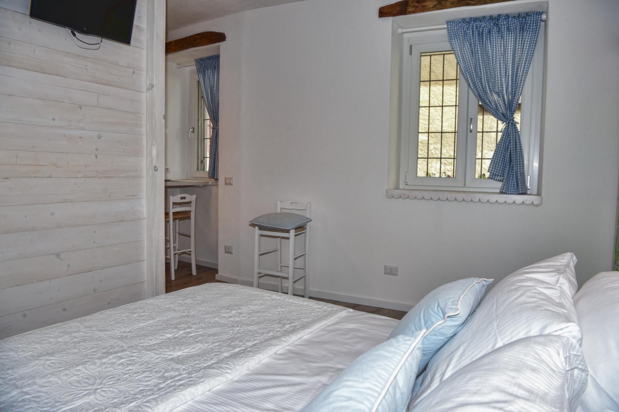 A bedroom with a bed, a small desk, and a window with curtains.