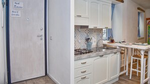 A kitchen with white cabinets, a tiled backsplash, and a gas stove. There are two signs on the door: "Non fumare" and "Don't Smoke". - Ca de Sota by Wonderful Italy (Bellagio)