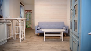 A room with a light blue sofa, a white coffee table, and a wooden floor. There is a white cabinet with drawers on the left and a blue cabinet with circular handles on the right. - Ca de Sota by Wonderful Italy (Bellagio)
