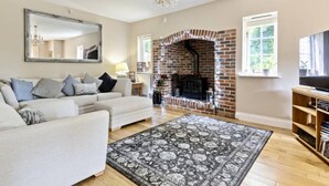 Una sala de estar con chimenea, sofás, una araña y un televisor.