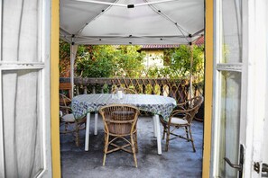 Alpendre aberto com mesa e cadeiras sob um toldo branco.