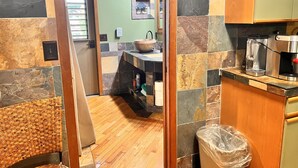 A kitchen with a stone backsplash, wooden cabinets, and a coffee maker. - Maui What A Wonderful B&B Pineapple Ste (Kihei)