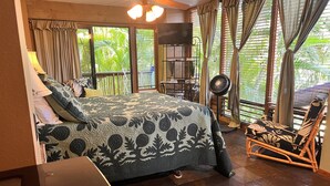 A bedroom with a bed, a desk, a chair, a fan, and a TV. - Maui What A Wonderful B&B Pineapple Ste (Kihei)