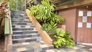 A staircase with stone steps leading to a wooden deck, surrounded by lush green plants. - Maui What A Wonderful B&B Pineapple Ste (Kihei)