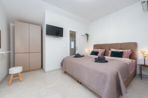 A bedroom with a bed, a wardrobe, a television, and a small table with a lamp. - A Stunning Vacation Home in Vrsi—A Beachfront Getaway with a Private Saltwater Pool (Vrsi)