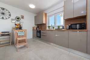 A modern kitchen with a built-in oven, microwave, and a wooden countertop.