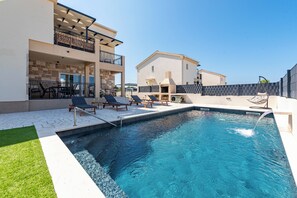 A swimming pool with lounge chairs and a stone-tiled deck.