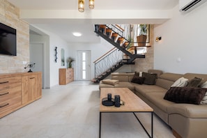 A modern living room with a sofa, coffee table, and a staircase leading to an upper level. - A Stunning Vacation Home in Vrsi—A Beachfront Getaway with a Private Saltwater Pool (Vrsi)