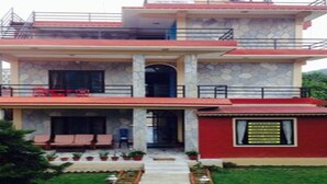 A two-story house with a balcony, a covered porch, and a small attached structure with a sign. - MeroStay 020 Unique Mountain Guest House (Pokhara)