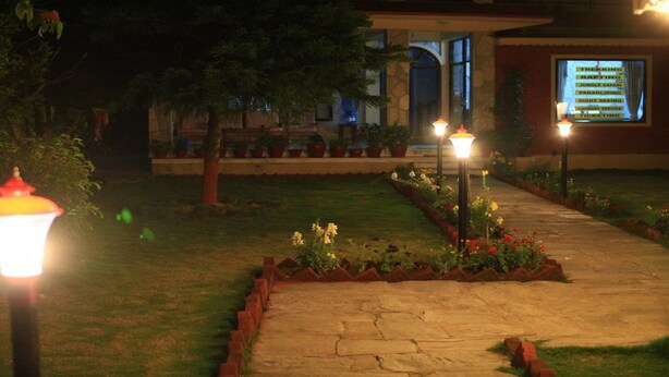 A well-lit pathway leading to a building with a signboard listing amenities like trekking, rafting, and safari. - MeroStay 020 Unique Mountain Guest House (Pokhara)