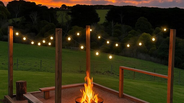Un foyer extérieur entouré de guirlandes lumineuses, installé dans un espace verdoyant.