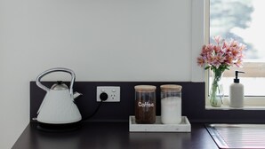 Un plan de travail de cuisine avec une bouilloire, des pots à café et un vase rempli de fleurs.