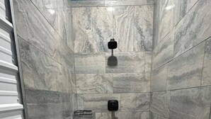 Una ducha con techo azul, paredes de mármol y suelo de baldosas.