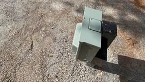 A gravel parking area with a water pump and a mailbox.