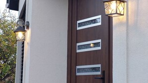 Une porte en bois avec trois panneaux de verre rectangulaires et une poignée noire.