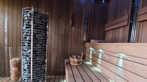 Un sauna avec un banc en bois, un appareil de chauffage en pierre et un mur en bois.