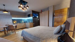 Une chambre moderne avec un grand lit, un bureau et un coin cuisine.