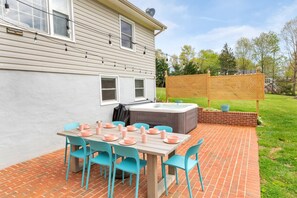 A patio with a brick floor, a wooden table, and turquoise chairs.