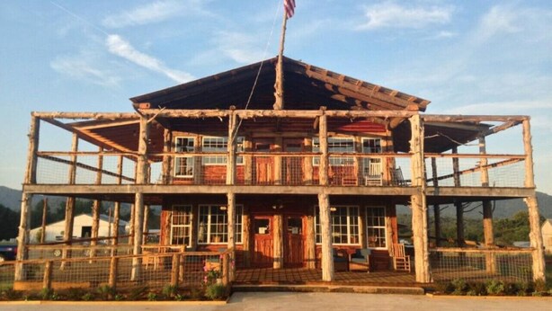 A rustic, multi-level wooden building with a balcony, an American flag, and a fenced entrance. - Ideal for family summer vacations or a few couples wine weekend/mountain getaway (Lovingston)