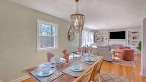 A dining area with a wooden table set for four, a chandelier, and a white sofa in the background. - Ideal for family summer vacations or a few couples wine weekend/mountain getaway (Lovingston)