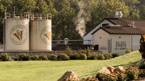 A distillery with two large cylindrical silos, a building with a sign reading "Great Whiskey Starts as a Journey," and a grassy area with rocks and shrubs. - Ideal for family summer vacations or a few couples wine weekend/mountain getaway (Lovingston)