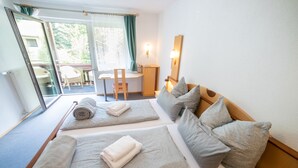 A hotel room with two beds, a desk, a chair, and a view of the outdoors.
