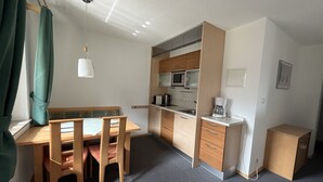 Cocina compacta con comedor, que incluye una mesa, sillas, microondas, cafetera y armarios.